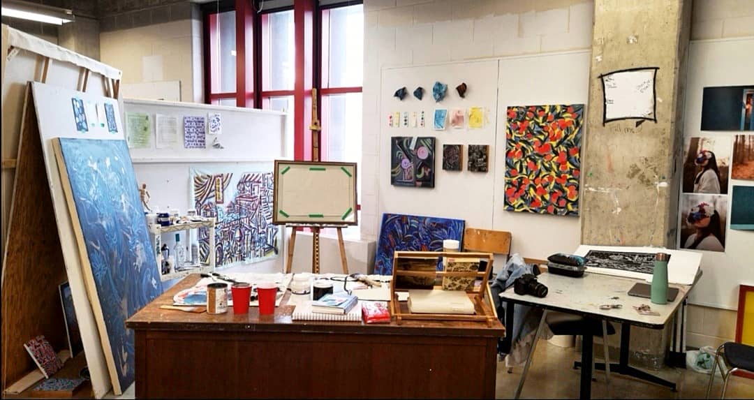 Photo of the artist's studio space, surrounded with paintings